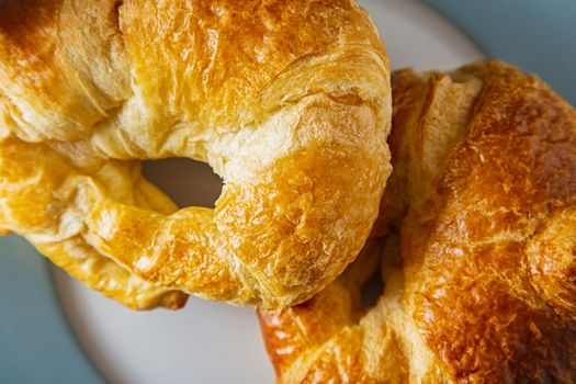 close up top view of two croissant on a blue rimmed plate