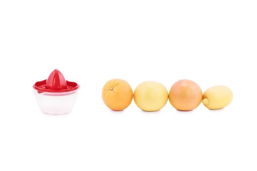 Close up shot of citrus fruits arranged in a line next to a manual juice squeezer, isolated on white background. Orange, grapefruit and lemon next to a juice squeezer.