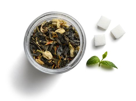 Green tea with natural aromatic additives and sugar. Top view on white background.