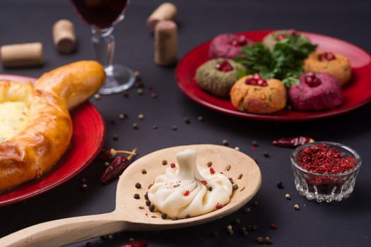 Georgian food on black table. khinkali, phali,  khachapuri with tomatos, adjika and a glass of wine.