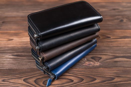 A stack of handmade leather wallets on wooden background