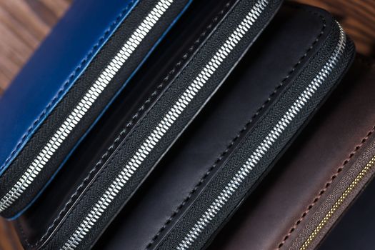 A stack of handmade leather wallets on wooden blurred background. Close up view.