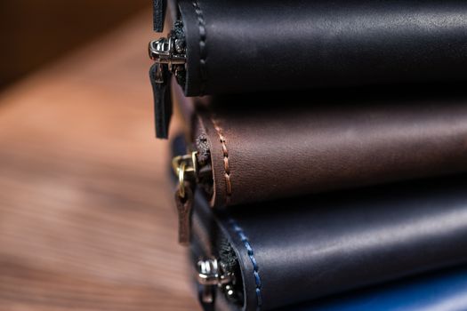 A stack of handmade leather wallets on wooden blurred background. Close up view.