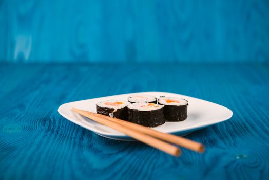 Appetizing tasty Japan rolls on a plate isolated on blue wooden background