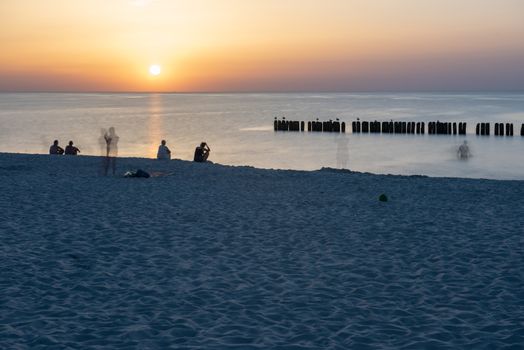 A photograph of wooden breakwater and seagulls at sunset on the Baltic Sea