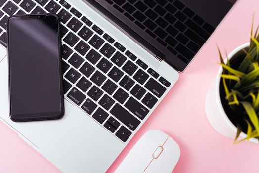 Top view of modern technology smart phone mobile and computer laptop on pink background with copy space