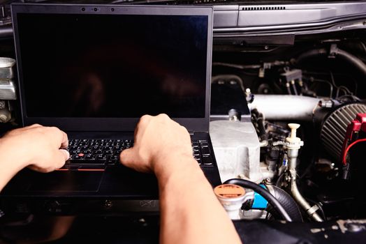 Professional car repair or maintenance mechanic engine working service with laptop computer at workshop