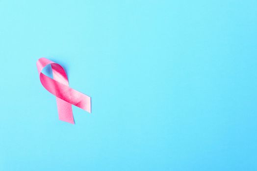 Breast cancer month concept, flat lay top view, pink ribbon on blue background with copy space for your text