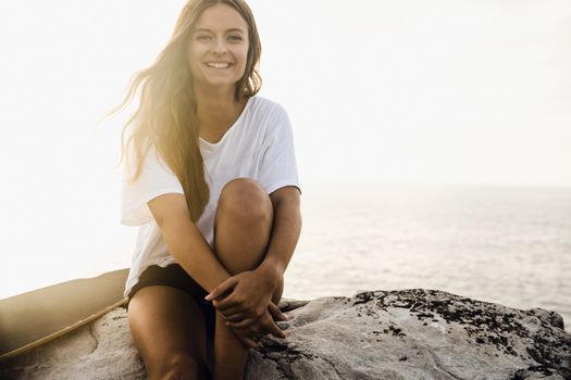 Beautiful and fashion young woman posing at the sunset with a skateboard