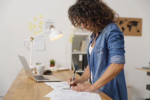 Middle age woman at the office working on with a  laptop