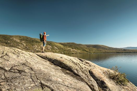 Shot of a man pointing to the beautiful view of the lake 