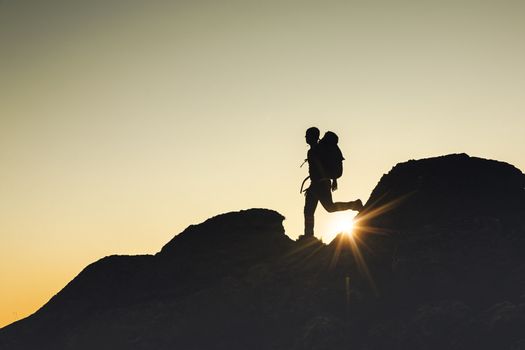 Shot of a man walking over the montains at sunset