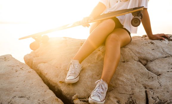 Young girl posing at the sunset with a skateboard