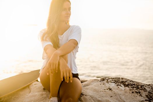 Beautiful and fashion young woman posing at the sunset with a skateboard