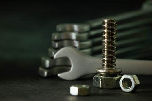 Bolt nuts and wrench on cement floor in darkness. Closeup and copy space for text. Concept of mechanical engineering jobs.