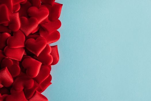 Valentine's day many red silk hearts on blue paper background , border frame on red with copy space, love concept
