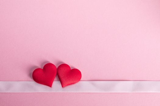 Valentine's day two red silk hearts and ribbon stripe on pink background, love concept