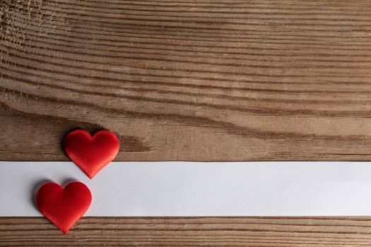 Valentine's day two red silk hearts and white paper on wooden background, love concept