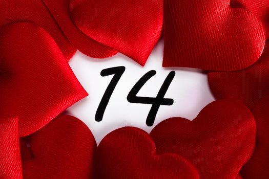 Valentine's day red silk hearts on calendar with 14 february date background, love, celebration concept