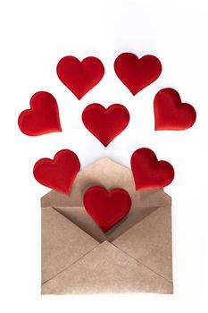 Valentine day love letter, envelope of craft paper with red hearts heap spread on white background.