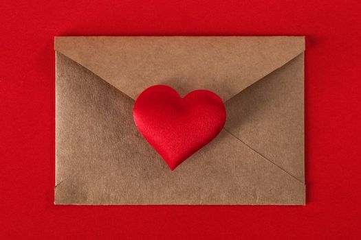 Valentine day love letter, envelope of craft paper with red heart on red background