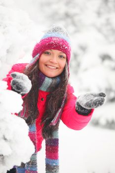 Young cheerful woman play snowballs in winter park