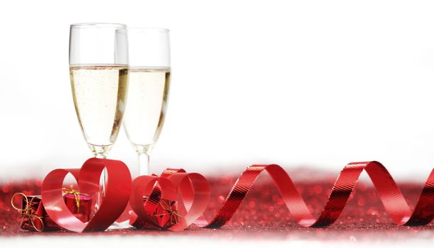 Glasses with Champagne and gifts on red glitters isolated on white background