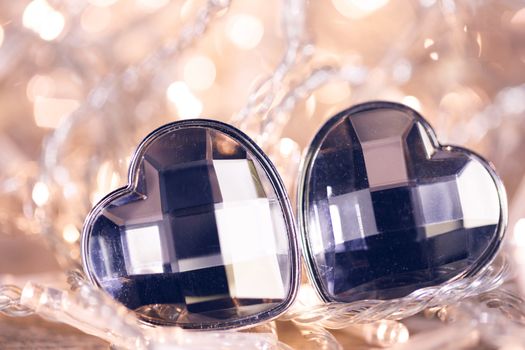 Two jewel hearts on golden shiny light garland background