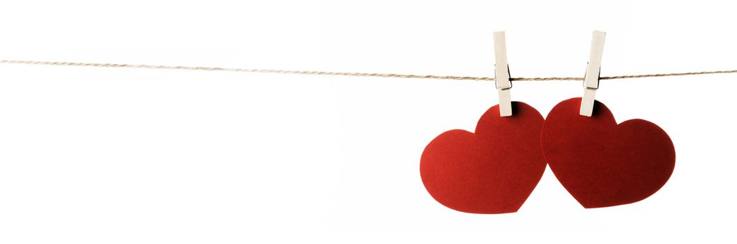 Clothes pegs and two red paper hearts on rope isolated on white background Valentines day concept
