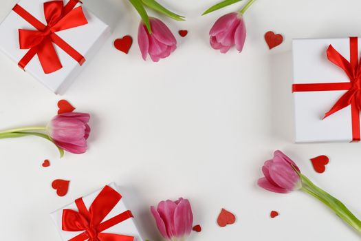 Pink tulip flowers gifts and red hearts composition on white background top view with copy space. Valentine's day, birthday, wedding, Mother's day concept. Copy space