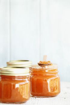A row of mason jars full of homemade Cantaloupe Jam against a rustic background. Extreme shallow depth of field with selective focus on center jar. Image could also be used for peach jelly or a marmalde. 