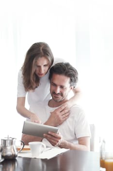 Couple having breakfast at home and using tablet