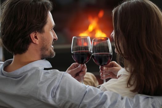 Romantic couple drinking wine at home near fireplace