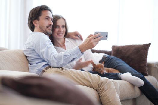 Happy couple taking a selfie together on the couch at home