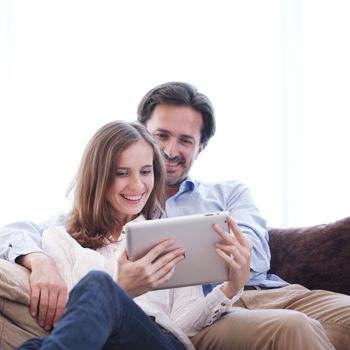 Cheerful couple using digital tablet at home