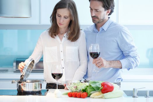 Portrait of a couple having a glass of red wine while cooking dinner