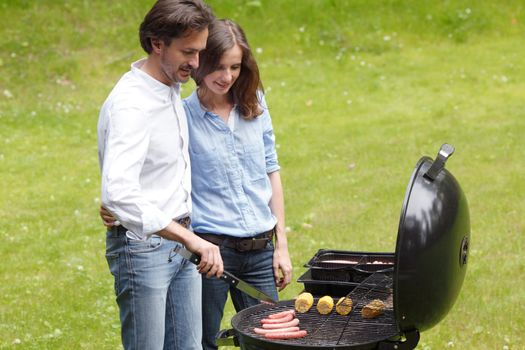Happy couple cooking food on barbecue