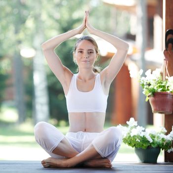 Young woman doing yoga lotus exercise outdoors