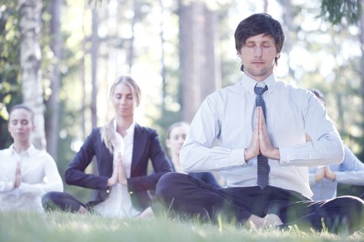 Business people practicing yoga in park