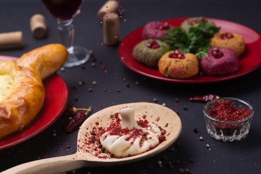 Georgian food on black table. khinkali, phali,  khachapuri with tomatos, adjika and a glass of wine.