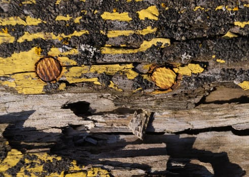 A part of old yellow wooden fence. The yellow paint on wood is old and cracked. Perfect painted wooden texture.