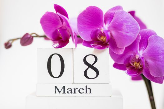 Date white block calendar for International Women's Day, March 8, decorated with orchid flower