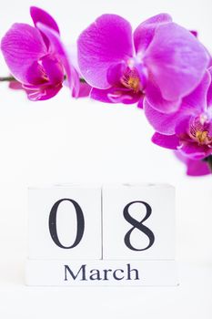 Date white block calendar for International Women's Day, March 8, decorated with orchid flower