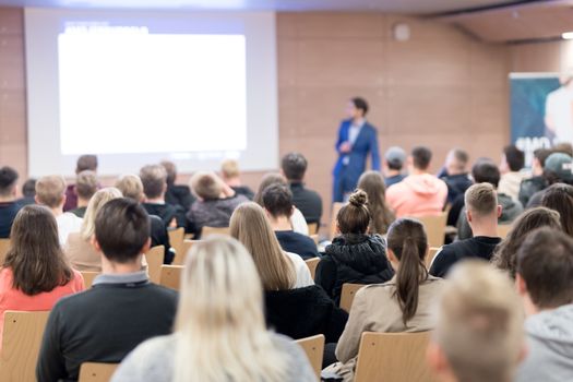 Speaker giving a talk in conference hall at business event. Audience at the conference hall. Business and Entrepreneurship concept. Focus on unrecognizable people in audience.