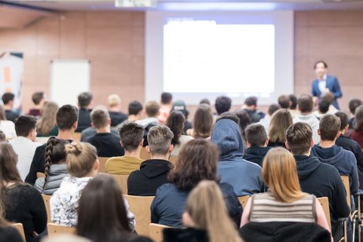 Speaker giving a talk in conference hall at business event. Audience at the conference hall. Business and Entrepreneurship concept. Focus on unrecognizable people in audience.