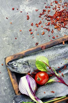 Fresh whole raw trout on a kitchen board.Fresh fish with vegetables and seasonings.