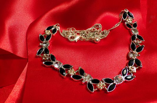 A necklace with diamonds and emeralds on a red silk fabric. Expensive jewelry.
