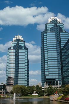 Twin blue office towers by lake against blue sky
