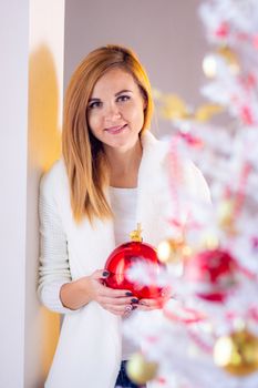 Portrait of a girl with a Christmas ball at a Christmas tree