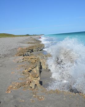 dirty blue ocean water splashing on rocks on the beach at coast